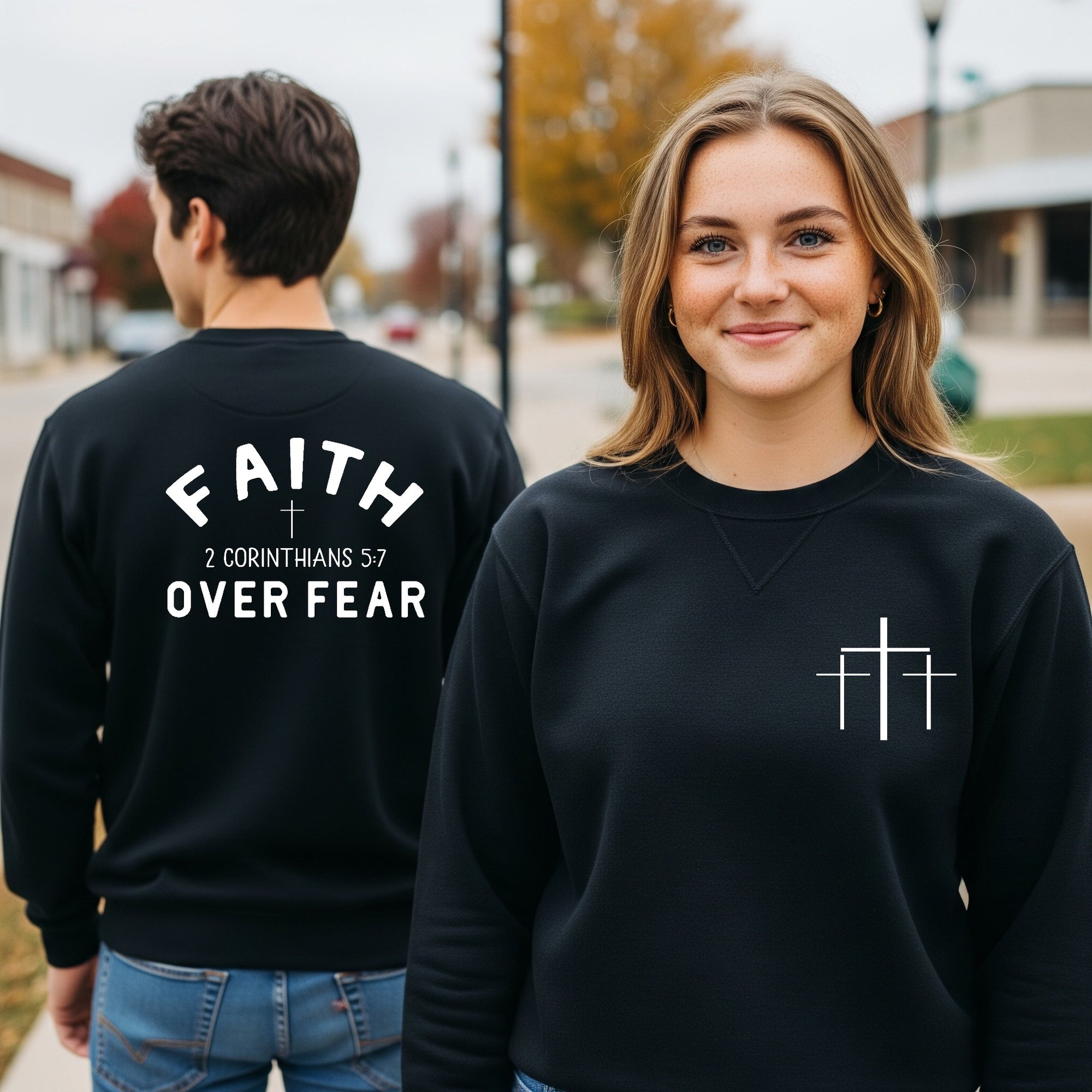 Two people wearing black sweatshirts with text and symbols, one with 'Faith Over Fear' on the back.